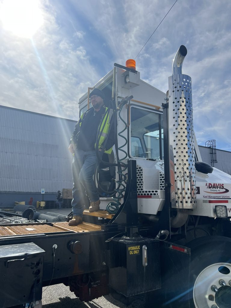 A man standing on the back of a semi truck